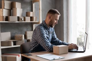 Foto: Mann mit Laptop und Pakete