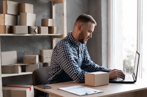 Foto: Mann mit Laptop und Pakete